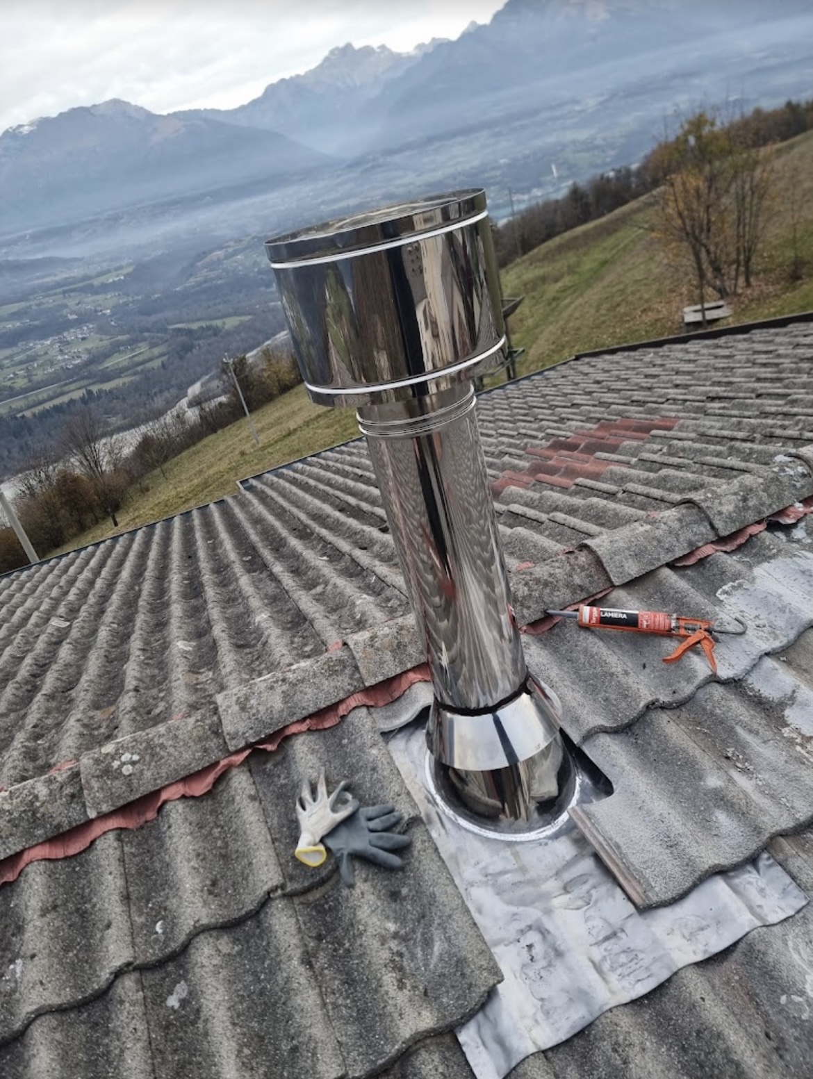 Canna fumaria inox lucido su tetto con vista sulle Dolomiti