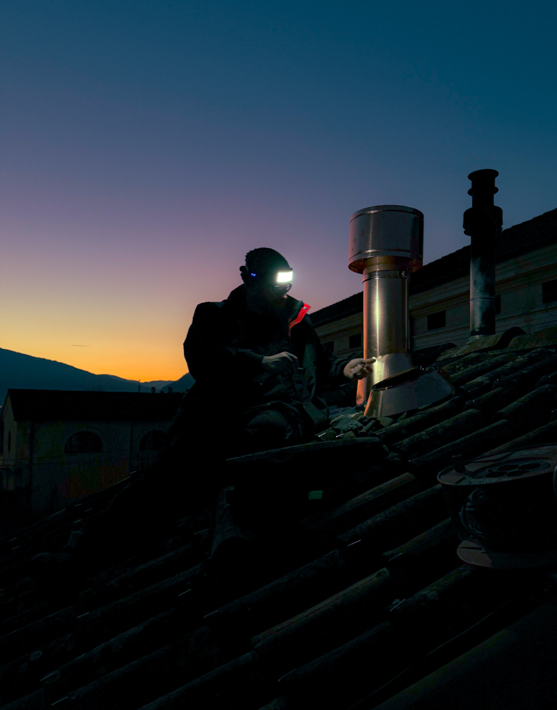 Tecnico TS Canne Fumarie al lavoro su un tetto al tramonto